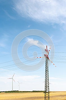 View of a wind power plant on a background of blue sky and fields with grain crops