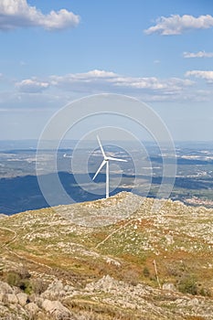 View of a wind turbine on top of mountains, blue sky as background