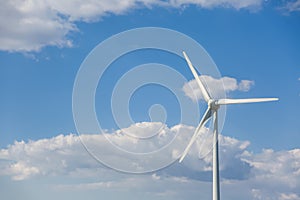 View of a wind turbine on top of mountains, blue sky as background