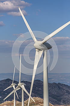 View of a wind turbine on top of mountains, blue sky as background