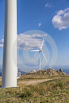 View of a wind turbine on top of mountains, blue sky as background