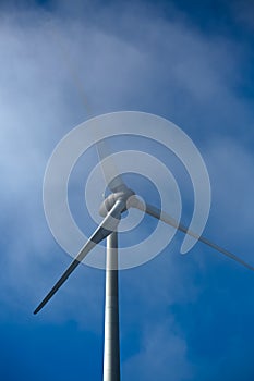 View of a wind turbine on top of mountains, fog on sky