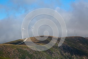 View of a wind turbines with fog on top of mountains landscape