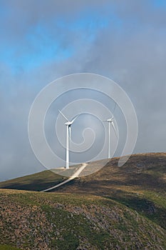 View of a wind turbines with fog on top of mountains landscape