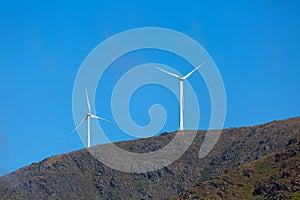 View of a wind turbines on top of mountains, cloudy sky as background