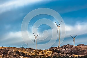 View of a wind turbines on top of mountains, dramatic sunset sky