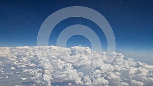 The view from the window of an air plane to the clouds, blue sunny sky.