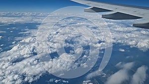 The view from the window of an air plane to the clouds, blue sunny sky.