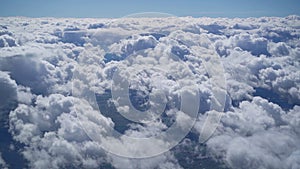 View from the window of an airplane on white fluffy clouds over the city on a clear sunny day, blue sky. Vacation travel by plane