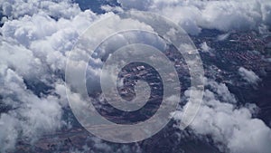 View from the window of an airplane on white fluffy clouds over the city on a clear sunny day, blue sky. Vacation travel by plane