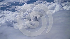 View from the window of an airplane on white fluffy clouds over the city on a clear sunny day, blue sky. Vacation travel by plane