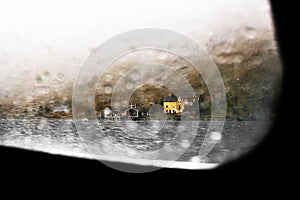 View through a window of a boat on ocean on to a remote village with colorful wooden cabins at the coast on Lofoten Islands Norway