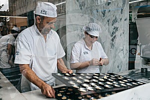 A view through the window of a cafe or glass as a chef prepares a traditional Portuguese dessert called Pastel de Nata.