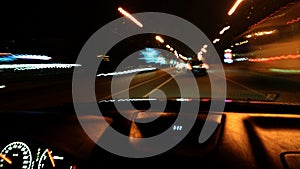 View from the window of a car driving fast along the  street of a night city.