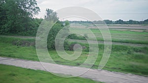 view from window of high-speed train on landscape of beautiful nature wild field and forest on evening cloudy clean