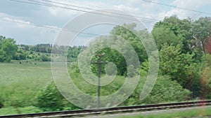 view from window of high-speed train on landscape of beautiful nature wild field and forest on evening cloudy clean