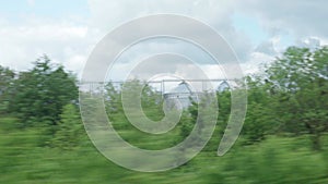 view from window of high-speed train on landscape of beautiful nature wild field and forest on evening cloudy clean