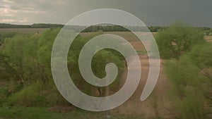 view from window of high-speed train on landscape of beautiful nature wild field and forest on evening cloudy dusk sky