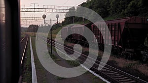 view from window high-speed train on old abandoned station and rusty freight wagons railroad tracks rails on evening sky