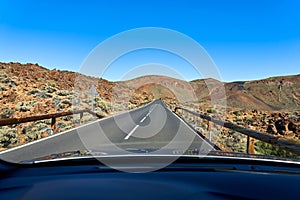 View from the window of a moving car on an empty and deserted highway in the desert with rocks and cacti