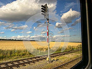 View from window of moving train at red traffic light in beautiful summer landscape