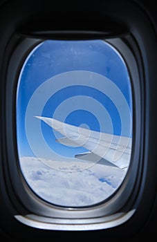 View through the window of the plane on Airplane wing on the blue sky