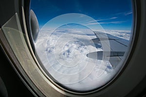 View from the window of the plane onto the wing and engines of a fokker 100 model with a blue sky and white clouds. Sunny weather