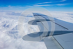 View from the window of the plane onto the wing and engines of a fokker 100 model with a blue sky and white clouds. Sunny weather