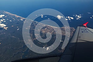 View from the window of the plane on the wing, the earth and the sea