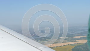 View from the window of a small passenger private plane against the backdrop of a white wing. Top view of houses, green