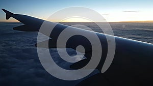 View from the window on the wing of an airplane flying over thick clouds. Beautiful feathery fence. Dawn in the air