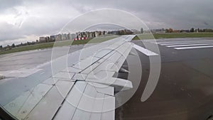 View from the Window on the Wing of an Airplane moving along the Runway at Airport