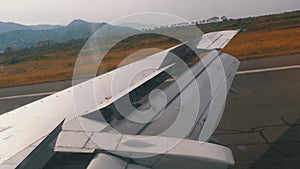 View from the Window on the Wing of an Airplane moving along the Runway at Airport after Landing