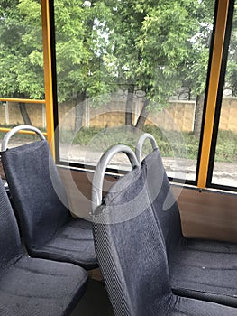 View from the window of the yellow bus and the gray empty seats in the foreground