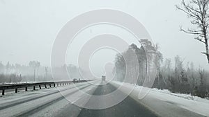 View through the windshield of a car on the autobahn in winter in heavy snowfall and a truck.