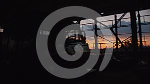 View of the windshield of a truck among the metal structures of an abandoned warehouse without walls at sunset
