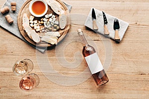 View of wine glasses, bottle of wine, sauce, bread, cheese, olives, corks and cooking utensils on wooden surface