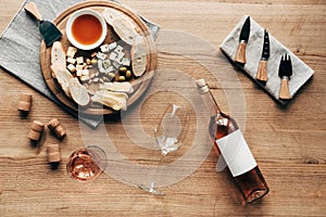 View of wine glasses, bottle of wine, sauce, bread, cheese, olives, corks and cooking utensils on wooden surface