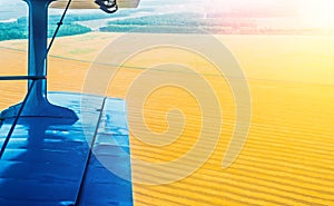 A view of the wing of a turboprop aircraft and a field of corn and wheat in the countryside