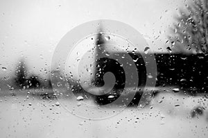 View on winter church through wet windshield with rain drops. Black and white