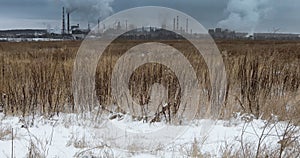 View of winter landscape with industrial plant ejecting smoke
