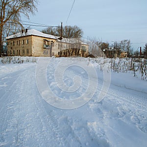 View of the winter road and old two-storeyed beige house