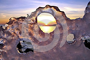 View of winter sunset through holes in ice