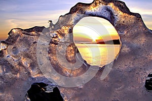 View of winter sunset through holes in ice