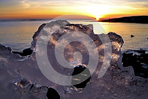 View of winter sunset through holes in ice