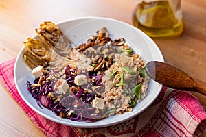 View of winter vegetarian bowl with red cabbage, mushrooms, tofu, spelt cereal, endive and radicchio on wooden table. Example of