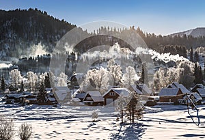 View of the winter  the village Iogach against the background of forested mountains. Altai Republic