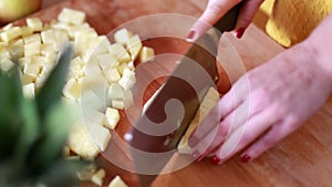 View of woman hands cutting pineapple on small pieces