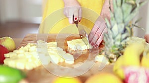 View of woman hands cutting pineapple on small pieces