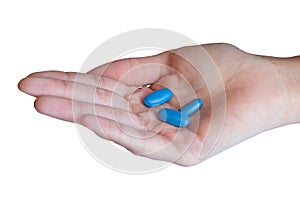 Woman holding three blue pills in her hand